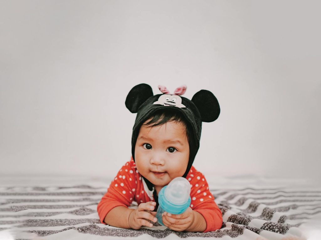 Baby in Red and White Polka Dot Long Sleeve Shirt Holding Blue and White Feeding Bottle - Eco-Friendly Baby Products